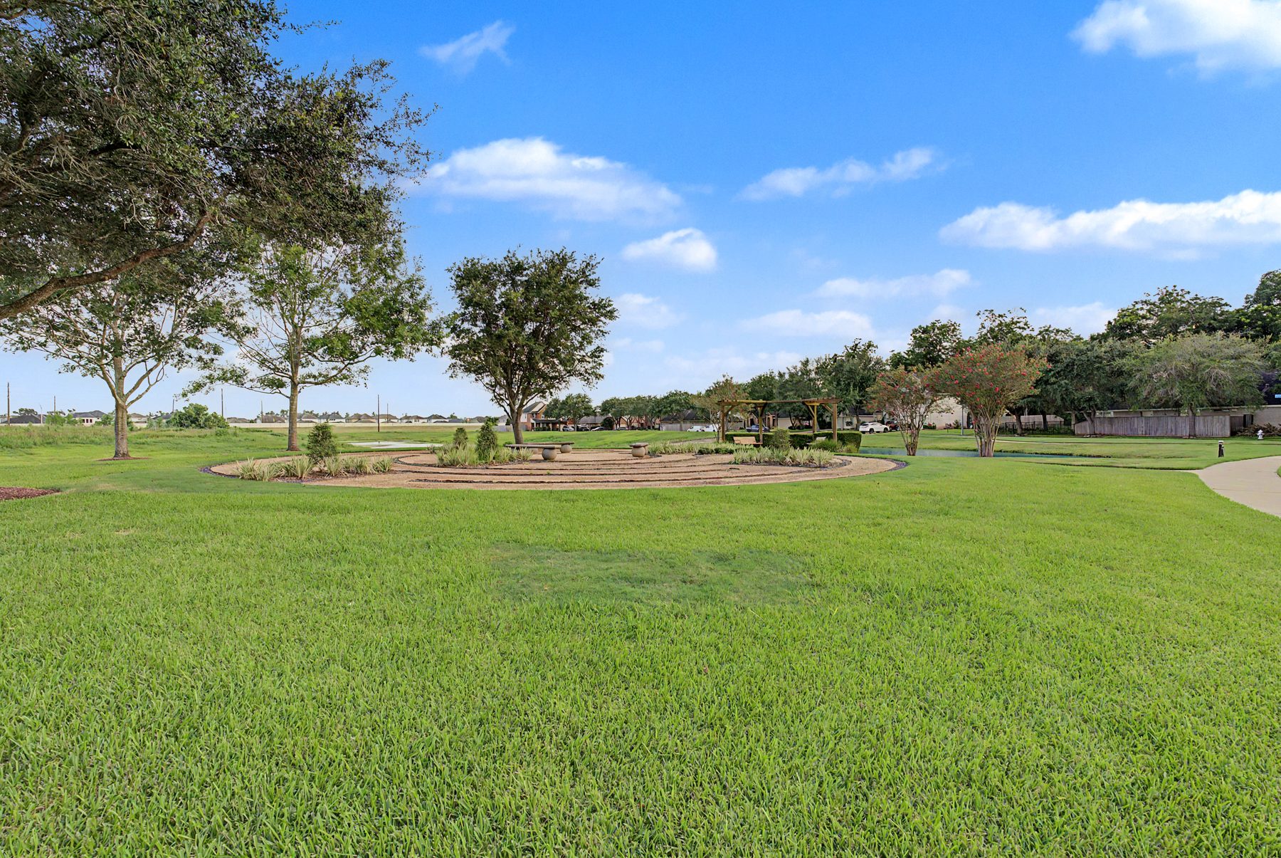Open park green and circular garden with pergola in Sienna, Missouri City TX