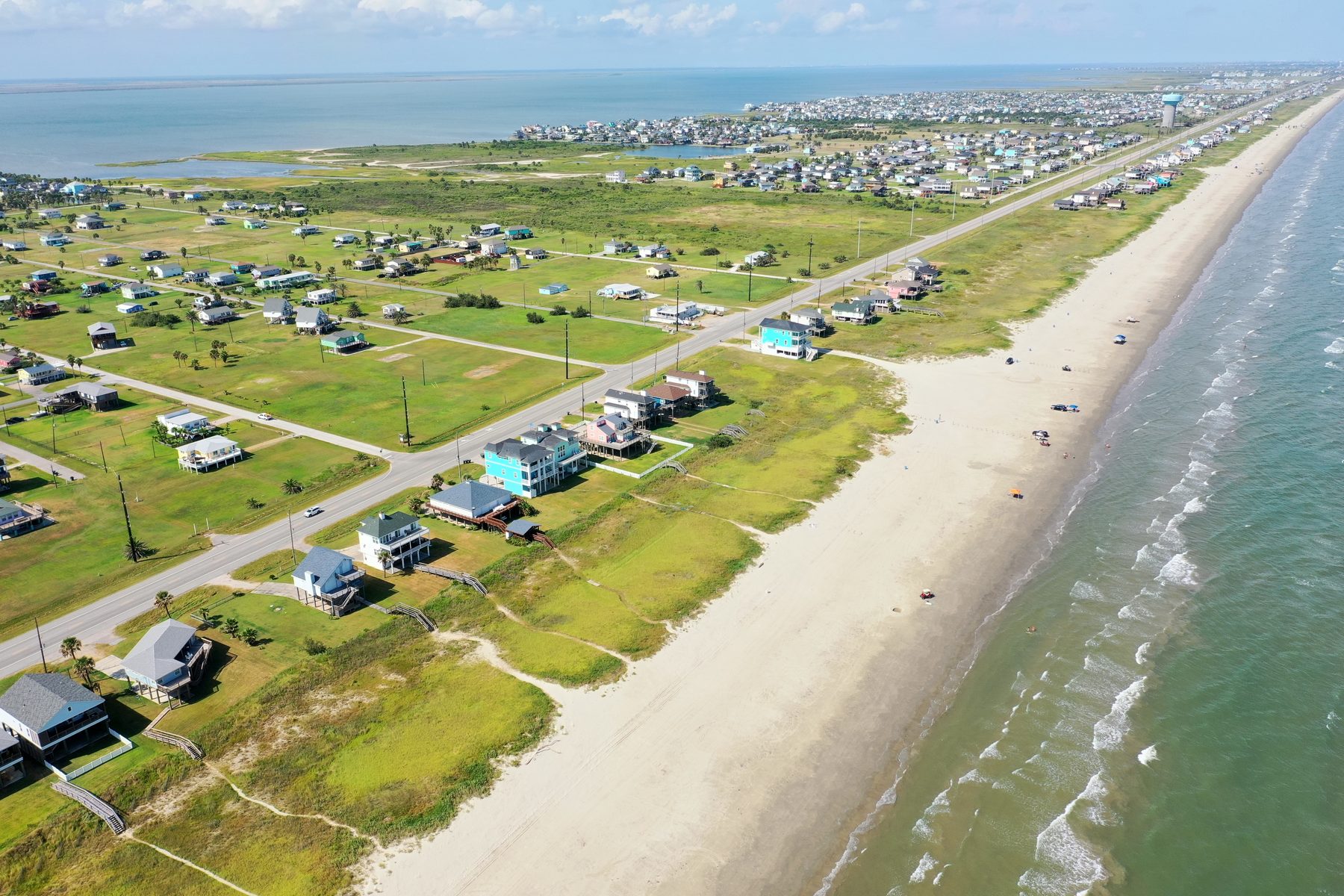 Aerial view of the narrow Galveston West End with homes between the bay and the Gulf