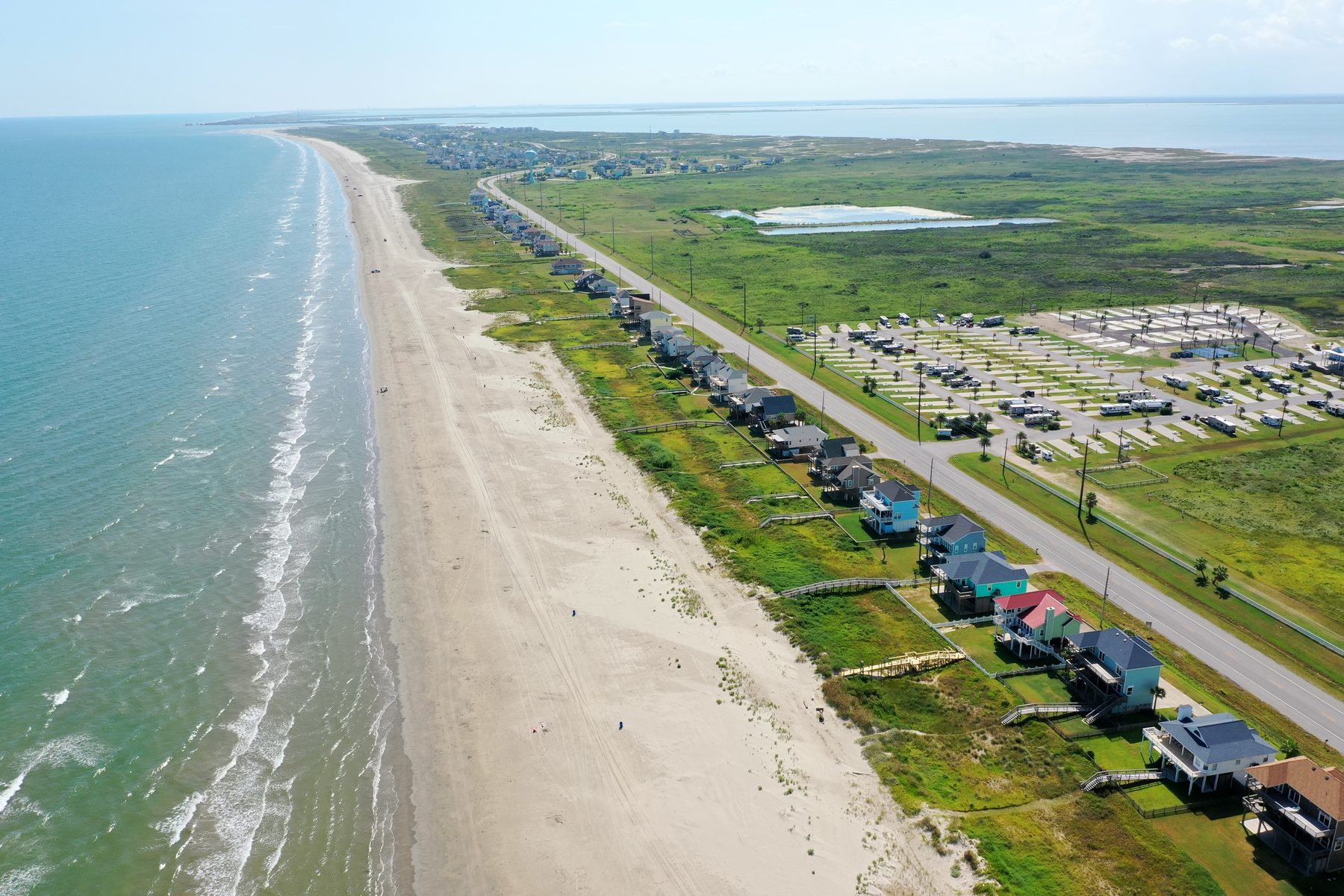 Aerial view of elevated beach houses lining the Gulf shore on the Galveston West End