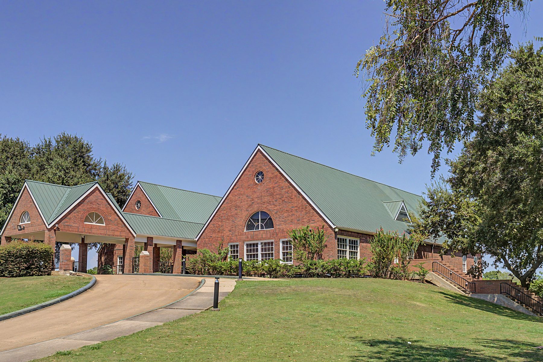 Brick clubhouse with green metal roof and covered drive at Greatwood Golf Club in Sugar Land