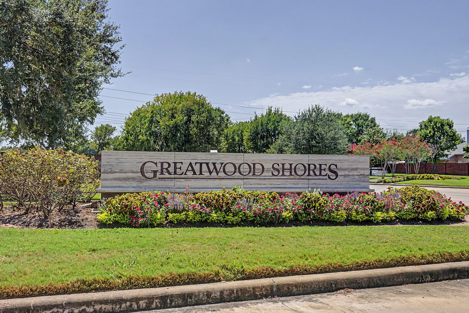Greatwood Shores stone monument sign with flower beds at a neighborhood entrance in Sugar Land